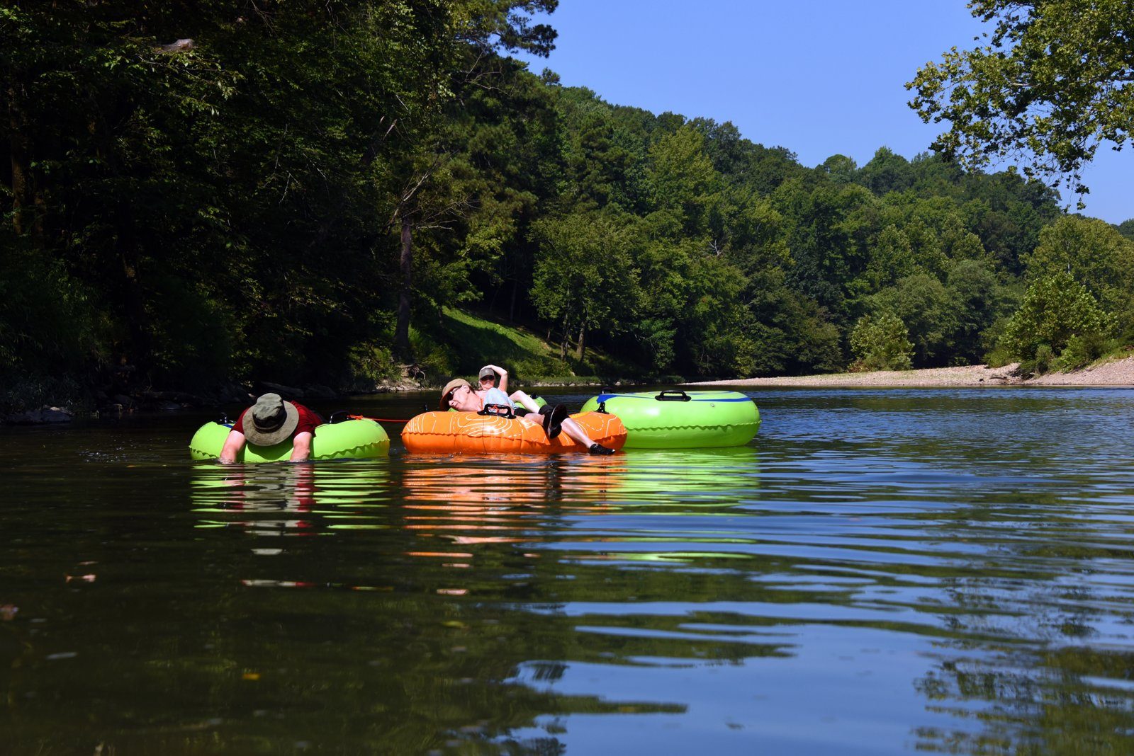 Texas family reunion fun: people floating on colorful tubes on the Brazos River with green trees along the bank