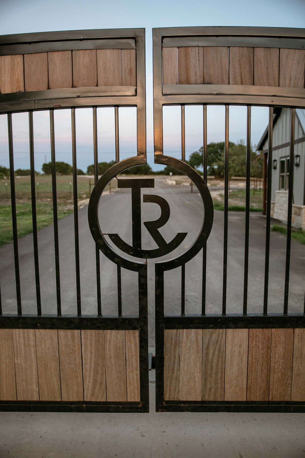 Sporting clays in Texas start here: the black iron and wood TCR entrance gate with the round brand in the center